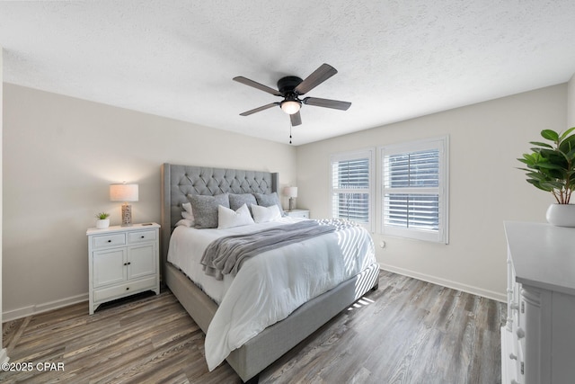 bedroom with a ceiling fan, wood finished floors, baseboards, and a textured ceiling
