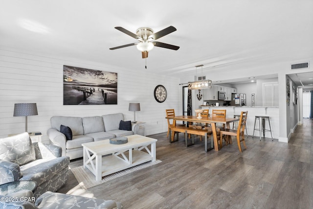 living area featuring dark wood finished floors, baseboards, visible vents, and ceiling fan