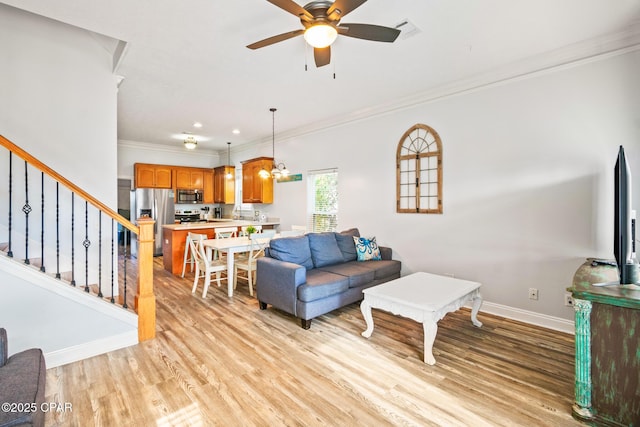 living area featuring light wood finished floors, visible vents, baseboards, stairs, and ornamental molding