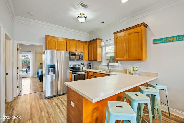 kitchen featuring visible vents, brown cabinets, a sink, appliances with stainless steel finishes, and a peninsula