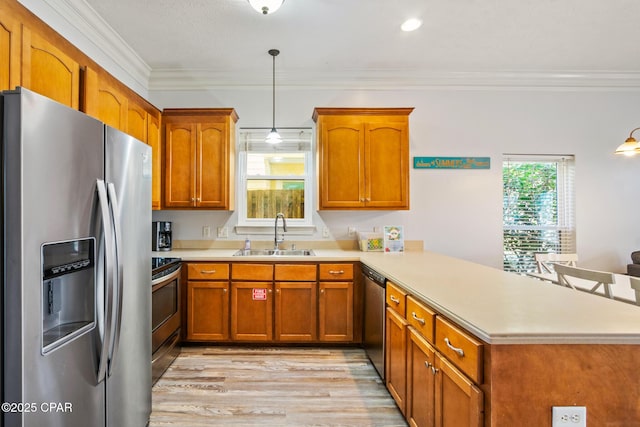 kitchen with brown cabinetry, a peninsula, a sink, stainless steel appliances, and light countertops