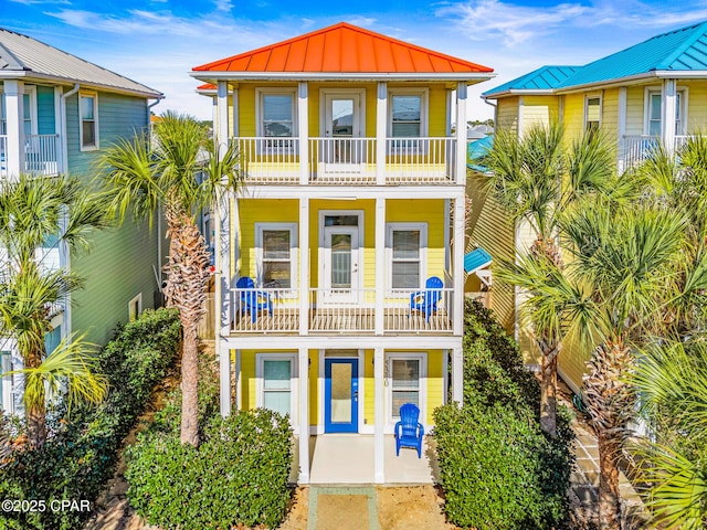 coastal inspired home with a balcony, metal roof, and a standing seam roof