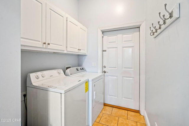 laundry room featuring washing machine and clothes dryer, light tile patterned floors, cabinet space, and baseboards