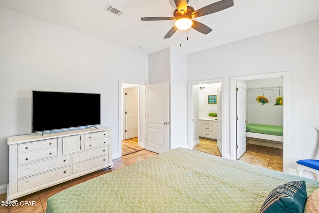 bedroom featuring light tile patterned floors, visible vents, ensuite bath, and a ceiling fan