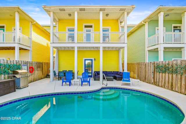 rear view of property with a fenced in pool, fence, outdoor lounge area, and a patio area