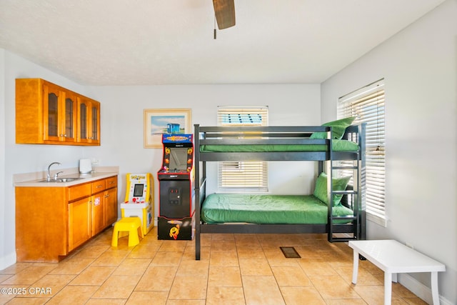 bedroom featuring a sink, baseboards, a ceiling fan, and light tile patterned floors