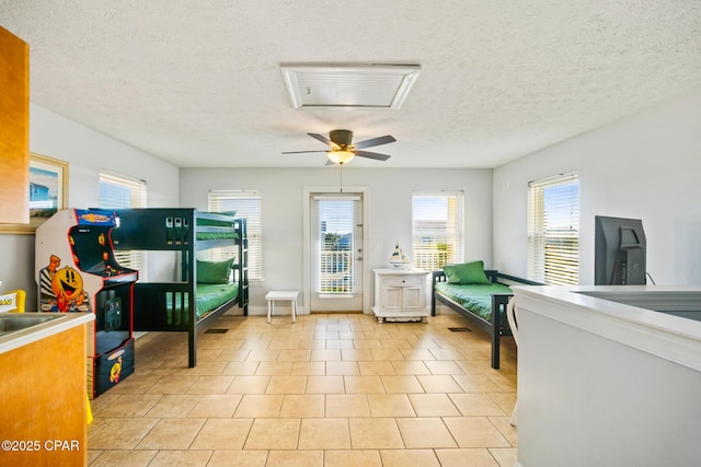 living area featuring light tile patterned floors, a textured ceiling, and a ceiling fan