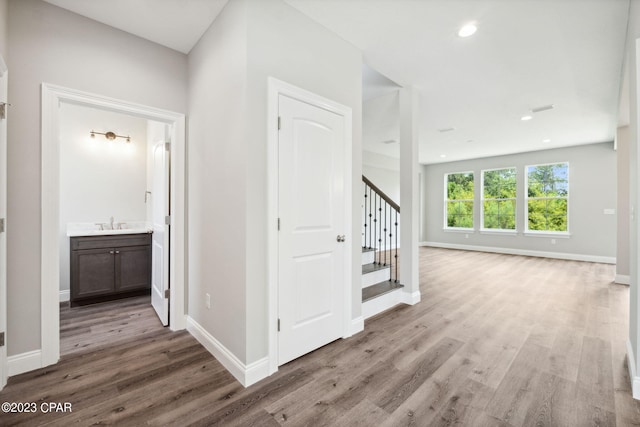corridor with baseboards, stairs, and wood finished floors