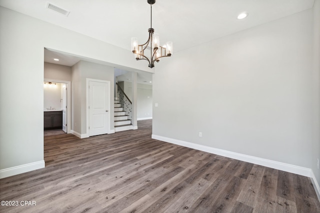 unfurnished dining area featuring a notable chandelier, stairway, baseboards, visible vents, and dark wood-type flooring
