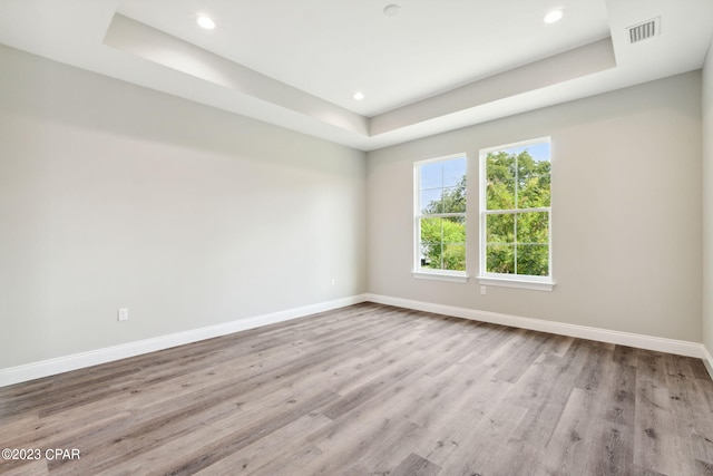 spare room with visible vents, baseboards, wood finished floors, recessed lighting, and a raised ceiling