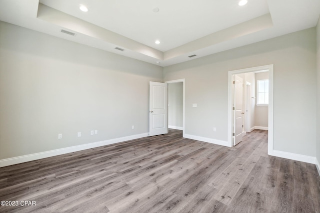 unfurnished bedroom with a raised ceiling, baseboards, and wood finished floors