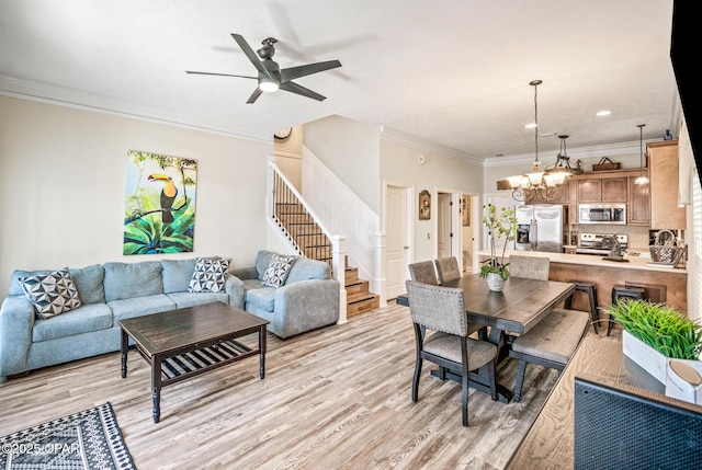 living area featuring recessed lighting, stairs, crown molding, ceiling fan with notable chandelier, and light wood-type flooring