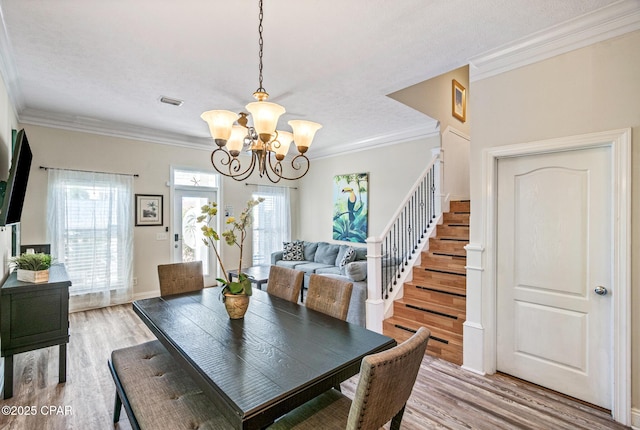 dining space featuring wood finished floors, an inviting chandelier, crown molding, baseboards, and stairs