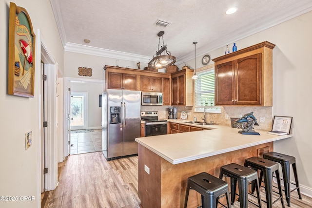 kitchen featuring visible vents, decorative backsplash, a peninsula, stainless steel appliances, and a sink