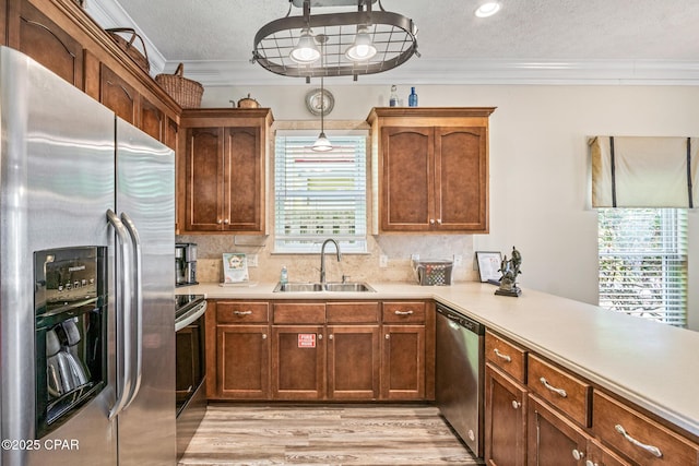 kitchen with ornamental molding, appliances with stainless steel finishes, light countertops, and a sink