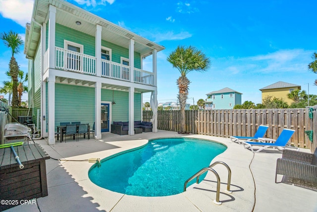 rear view of house with a patio area, a fenced in pool, a fenced backyard, and a balcony