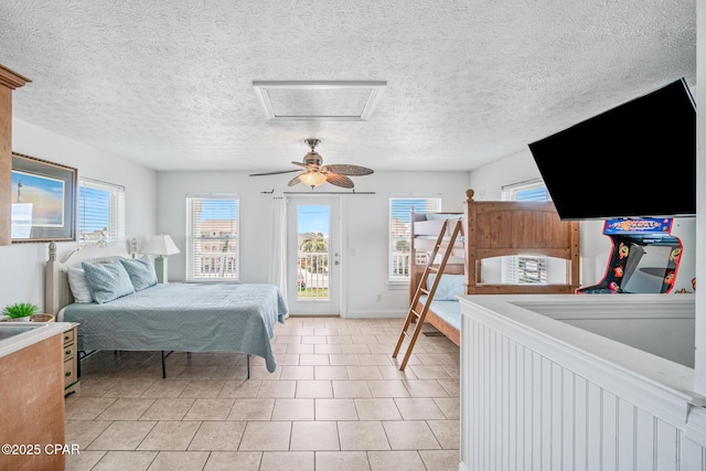 bedroom featuring access to exterior, attic access, multiple windows, and ceiling fan