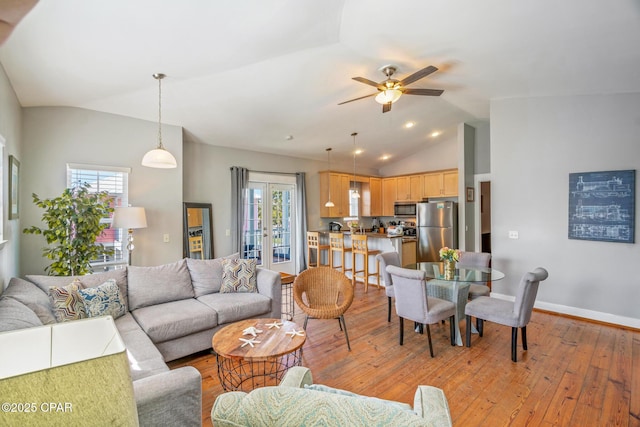 living area featuring baseboards, lofted ceiling, ceiling fan, and light wood finished floors