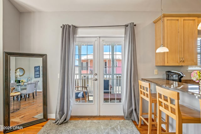 doorway to outside with light wood-style flooring and baseboards