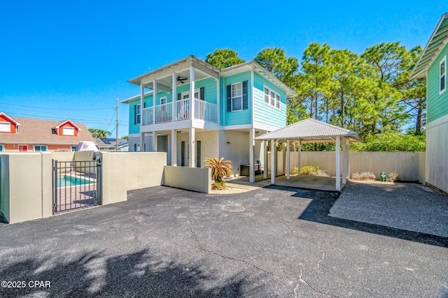 rear view of house with a ceiling fan, a balcony, and fence