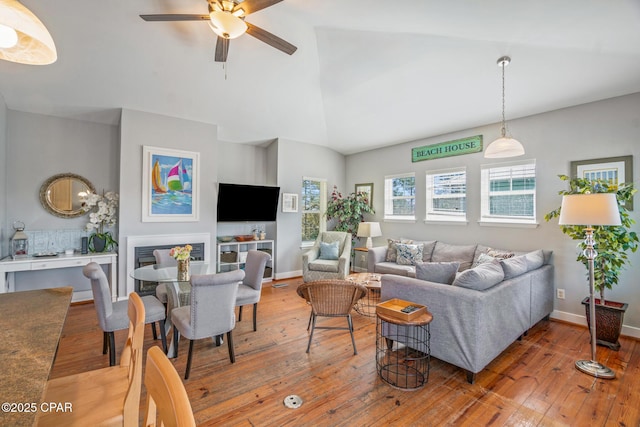 living room with baseboards, wood-type flooring, lofted ceiling, and a ceiling fan