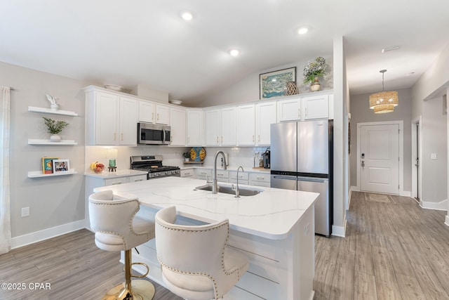 kitchen featuring decorative backsplash, white cabinetry, stainless steel appliances, and a sink