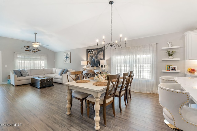 dining room featuring a wealth of natural light, ceiling fan with notable chandelier, wood finished floors, and vaulted ceiling