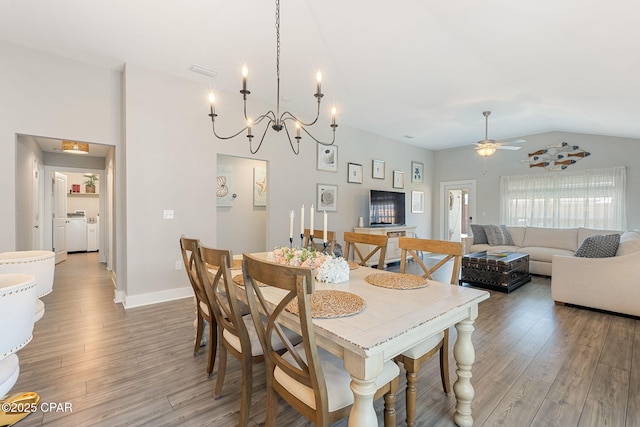 dining area featuring wood finished floors, baseboards, ceiling fan, vaulted ceiling, and washer and clothes dryer