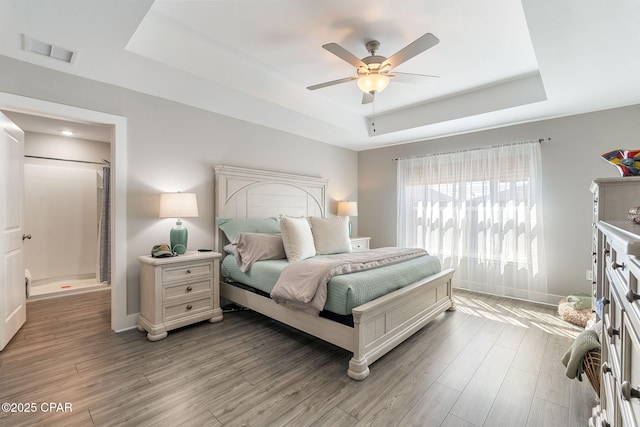 bedroom featuring visible vents, a raised ceiling, baseboards, and light wood-style flooring