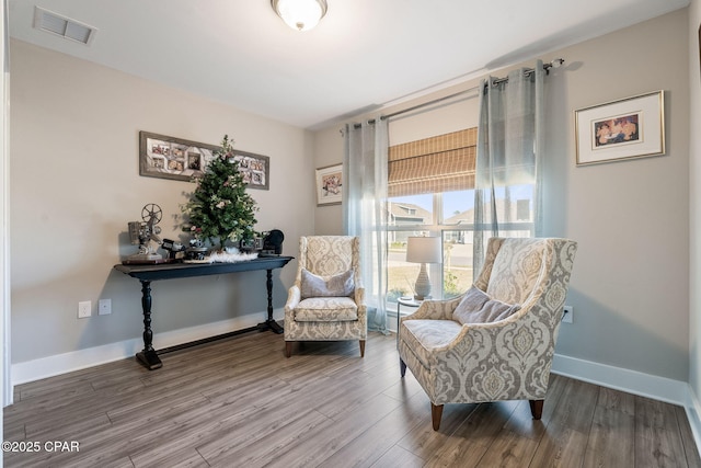 sitting room with wood finished floors, visible vents, and baseboards