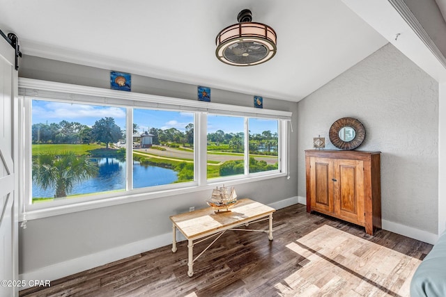 unfurnished room with baseboards, lofted ceiling, a barn door, and wood finished floors