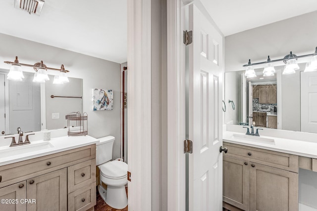 bathroom featuring visible vents, two vanities, and a sink