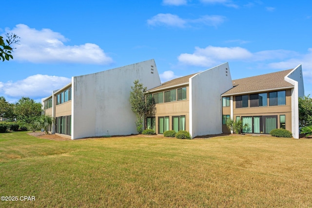 rear view of property with a lawn and stucco siding