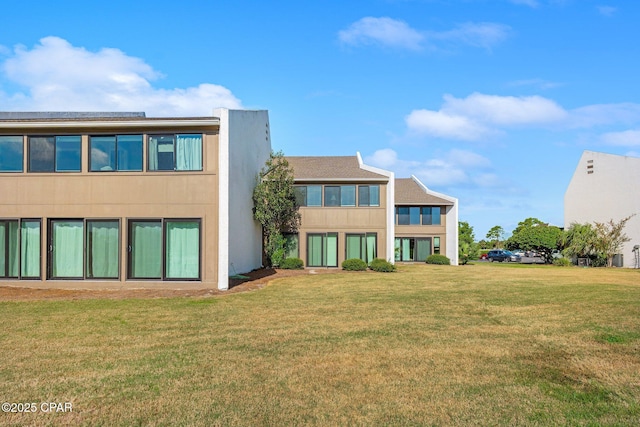 back of house with a yard and stucco siding