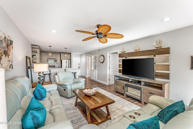 living room featuring recessed lighting, baseboards, a ceiling fan, and wood finished floors