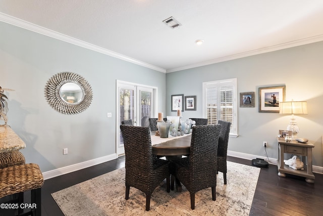 dining area featuring dark wood finished floors, visible vents, baseboards, and ornamental molding