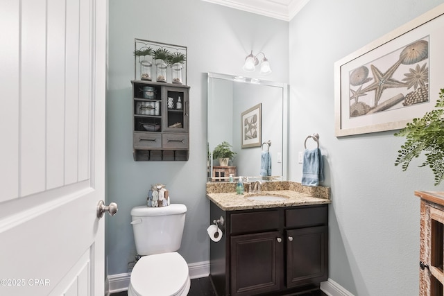 bathroom featuring toilet, vanity, baseboards, and ornamental molding