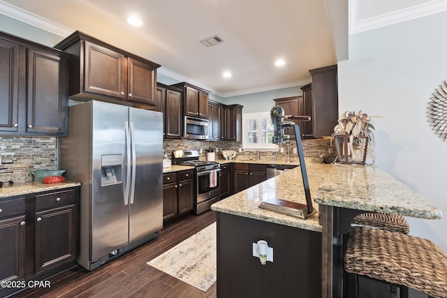 kitchen featuring dark brown cabinetry, ornamental molding, a peninsula, dark wood-style floors, and stainless steel appliances