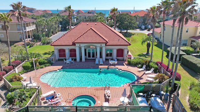 community pool with a patio area, fence, and a hot tub