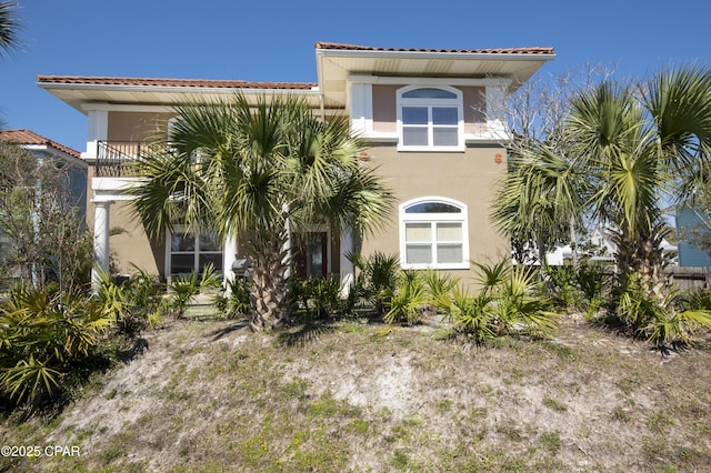 mediterranean / spanish-style house with a tile roof, a balcony, and stucco siding