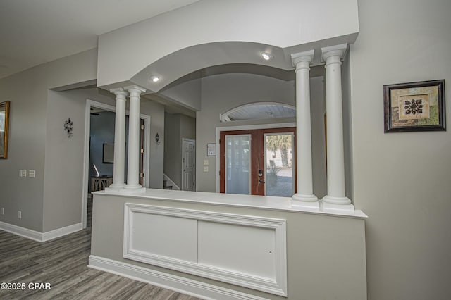 interior space with wood finished floors, french doors, arched walkways, decorative columns, and baseboards