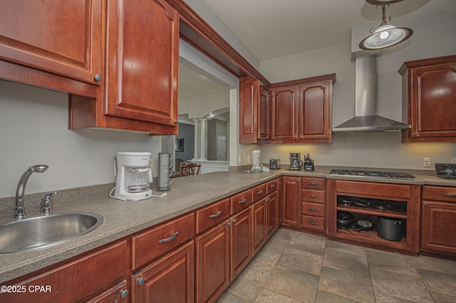 kitchen featuring wall chimney exhaust hood, stainless steel gas cooktop, ornate columns, and a sink