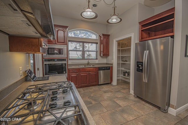 kitchen with a sink, appliances with stainless steel finishes, baseboards, extractor fan, and dark brown cabinets