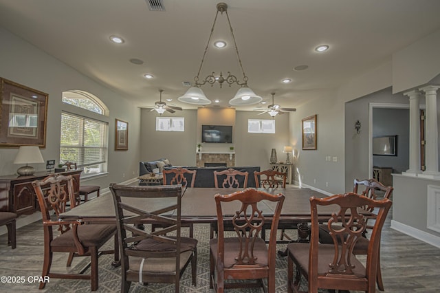 dining area with dark wood finished floors, decorative columns, a fireplace, recessed lighting, and ceiling fan