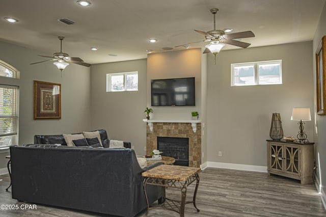 living room with wood finished floors, baseboards, visible vents, recessed lighting, and a tile fireplace