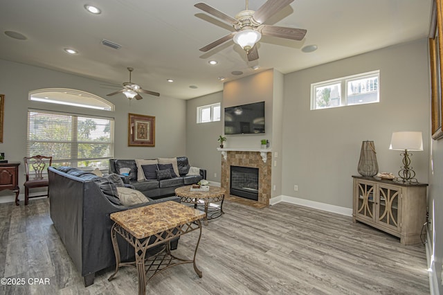 living area with light wood finished floors, visible vents, baseboards, recessed lighting, and a tile fireplace