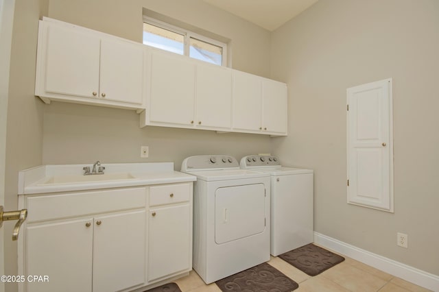 washroom featuring a sink, washer and dryer, cabinet space, light tile patterned floors, and baseboards