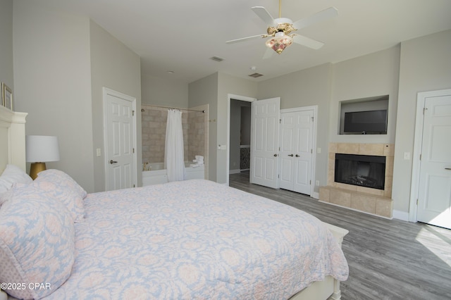 bedroom featuring visible vents, baseboards, wood finished floors, and a tile fireplace