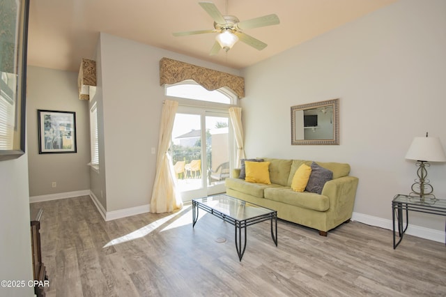 living room with a ceiling fan, baseboards, and wood finished floors