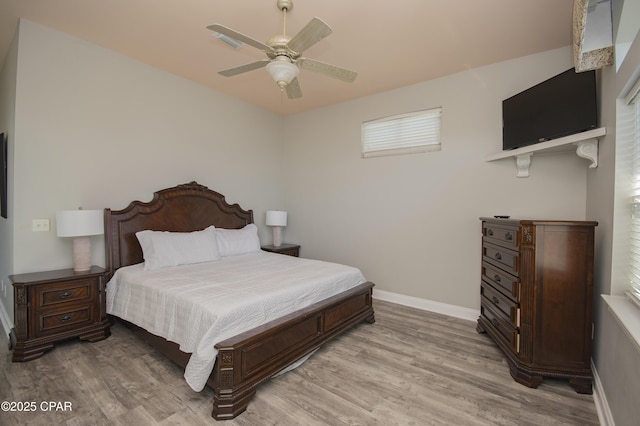 bedroom with light wood-style flooring, a ceiling fan, and baseboards